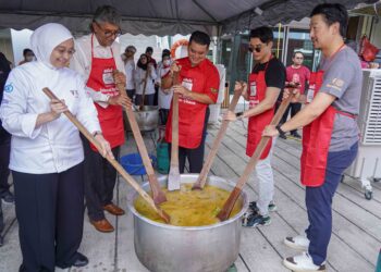 Adrian Roslan (tengah) dan Vuitton Pang (kanan) membantu memasak bubur lambuk di Taylor’s University, semalam. - UTUSAN/FARIS RUSADIO