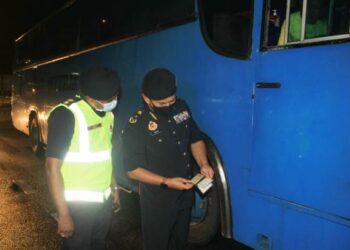 ADENAN Md. Isa memeriksa lesen pemandu bas pekerja dalam Ops Bas Pekerja di Jalan Paya Terubong, Pulau Pinang malam tadi. - FOTO/MUHAMMAD FIRDAUS AMRAN