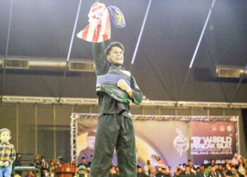 MOHD. Al Jufferi Jamari mengibar Jalur Gemilang sambil diperhatikan anaknya, Furqan Al Haq selepas menjuarai Kelas F pada Kejuaraan Pencak Silat Dunia Ke-19 berakhir di MITC, Ayer Keroh kelmarin. - UTUSAN/AMRAN MULUP