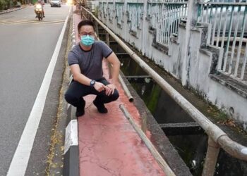 ANDREW Teow Chin Siang menunjukkan pagar penghalang yang rosak di Lintang Paya Terubong 2, Pulau Pinang yang dibimbangi membahayakan orang ramai.