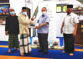 ABDUL Fattah Abdullah (dua dari kanan) menyerahkan pek barangan asas kepada penduduk kampung di Masjid Kampung Sungai Jai, Lenggeng, Seremban, hari ini. - FOTO/AFIFI HAFIZ MOHD. NOR