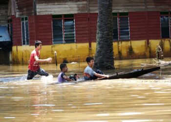 KANAK-kanak bermain air banjir yang melanda kampung mereka di Bagan Serai, Perak,  hari ini. - UTUSAN/ZULFACHRI ZULKIFLI