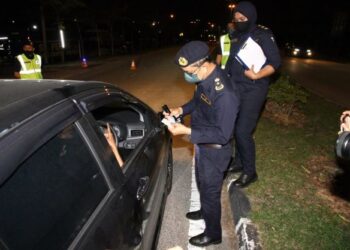 MOHAMMAD Yusoff Abustan memeriksa dokumen seorang pemandu kereta dalam Op HRAA di Meru, Ipoh semalam. - MUHAMAD NAZREEN SYAH MUSTHAFA