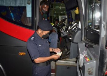 AZIZAN Hassan memeriksa dokumen pemandu bas ekspres dalam operasi bersepadu JSPT Perak ke atas bas ekspres di Terminal Meru Raya di Ipoh malam tadi. - UTUSAN/ZULFACHRI ZULKIFLI