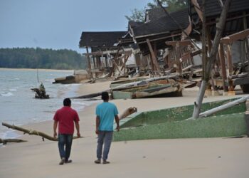 PENDUDUK kampung melewati sebahagian daripada 20 chalet yang dalam pembinaan dan runtuh akibat  hakisan di Pantai Telaga Papan, Setiu, Terengganu. – UTUSAN/PUQTRA HAIRRY ROSLI