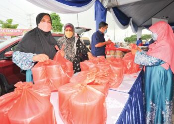 AHLI Helwa Masjid Sultan Iskandar membungkus bubur lambuk untuk diedarkan kepada para jemaah sempena  program Kongsi Berkat Bubuk Lambuk anjuran Era Foods MY dan Media Mulia Sdn. Bhd. di Tebing, Bandar Dato Onn, Johor Bahru kelmarin. – UTUSAN/RAJA JAAFAR ALI