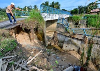 MOHD. Zairi Abdul Razak menunjukkan hakisan tebing sungai yang berisiko berlaku runtuhan jambatan ketika ditemui Utusan Malaysia di Ampangan, Seremban, semalam.-UTUSAN/MOHD. SHAHJEHAN MAAMIN.