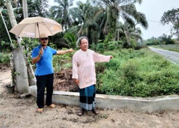 NORDIN MIAN (kanan)  dan Sulaiman Marsom menunjukkan keadaan parit ditumbuhi rumput yang didakwa menyekat  aliran air dan menyebabkan banjir kilat di Kampung Parit Sapran, Kayu Ara Pasong, Pontian.