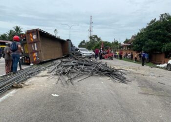 KEADAAN batang besi yang bertaburan di atas jalan raya selepas sebuah traler terbalik di simpang empat lampu isyarat di Kampung Dalam Kemunting, Pasir Puteh, Kelantan. - UTUSAN/TOREK SULONG.