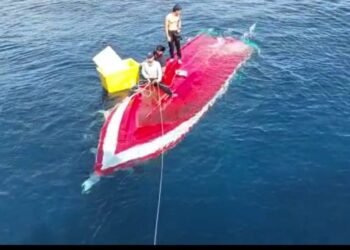 TANGKAP layar daripada video menunjukkan tiga nelayan berada di atas bot yang terbalik di perairan Pulau Kapas, Marang, hari ini.