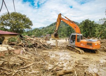 JENGKAUT membersihkan sisa kayu, pokok dan lumpur di kawasan rumah penduduk yang terlibat dalam tragedi kepala air di Kampung Iboi, Kupang, Baling, Kedah baru-baru ini. - UTUSAN/SHAHIR NOORDIN