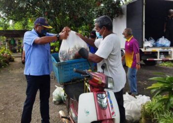 ABDUL Azeez Abdul Rahim (kiri) membantu salah seorang wakil penduduk kampung untuk memasukkan bekalan barangan makanan ke dalam motosikal ketika mengagihkan barangan tersebut di Kampung Bechah Sawa, Mukim Siong, baru-baru ini