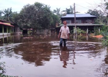 Seorang penduduk, Ayob Hassan meredah banjir di Kampung Matang Tengah Changkat Lobak, Bagan Serai, Perak. - UTUSAN/WAT KAMAL ABAS