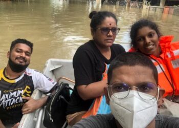 PENULIS (depan) dan keluarga diselamatkan dari kawasan banjir 
di Taman Sri Muda, Shah Alam, menggunakan bot.
