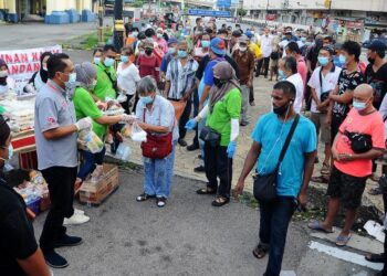 ZURAINI Tahir (kiri) menyampaikan bantuan makanan kepada gelandangan di Jalan Tun Razak, Johor Bahru semalam. – UTUSAN/RAJA JAAFAR ALI