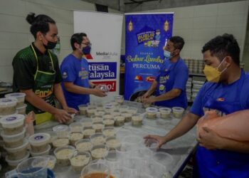 Petugas Media Mulia Sdn. Bhd. bersama Ahli Jawatankuasa Masjid Jamek Kampung Baru membantu Program Kongsi Berkat Bubur Lambuk anjuran Media Mulia dan Era Foods MY di masjid tersebut, kelmarin. – UTUSAN/AMIR KHALID