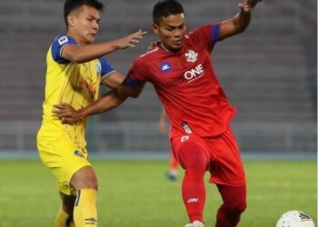 PERTAHANAN Tok Gajah, Muslim Ahmad (kiri) menyekat pemain PDRM pada perlawanan di Stadium Darul Makmur di Kuantan, hari ini.