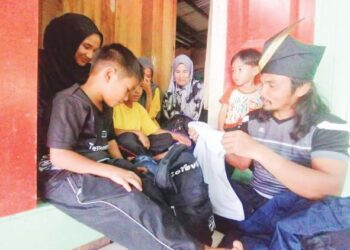 SYED Afindi Syed Mansor memilih pakaian sekolah anak-anaknya yang masih boleh dipakai di rumah mereka di Kampung Bukit Tokbat, Hulu Terengganu, semalam. – UTUSAN/NOOR HAYATI MAMAT