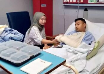 FATIN Nur Atirah Azizan melihat tangan suaminya, Mohamad Nizam Hamid yang cedera digigit beruang matahari semasa ditemui di HSAH, Sungai Petani. -UTUSAN/OTHMAN YAHAYA