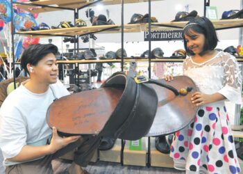SEORANG kanak-kanak, Suhana Abd. Rahim terpegun melihat capal gergasi yang ditunjukkan oleh Arif Syahmi Mohd. Shahril yang dipamerkan di gerainya di Angsana Johor Bahru Mall. semalam. -UTUSAN/RAJA JAAFAR ALI