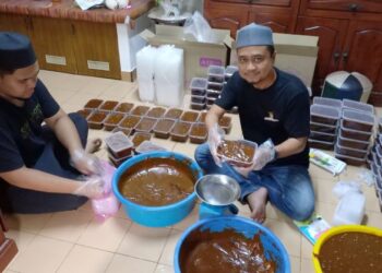 AMRAN Ali dibantu anak saudaranya membungkus dodol yang ditempah di Kampung Pernu, Melaka. - UTUSAN/AMRAN MULUP