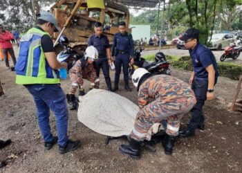 ANGGOTA Bomba dan Penyelamat mengangkat mangsa yang maut dihempap jentolak yang dibaikinya di tapak pelupusan sampah di Tanjung Langsat, Pasir Gudang. - IHSAN BOMBA