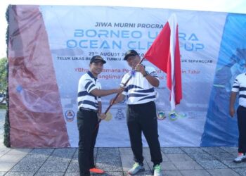 MOHD. RAZIB Tahir (kanan) menyerahkan bendera kepada wakil pegawai yang terlibat dalam program Borneo Ultra Ocean Clean-Up 2022 sebagai simbolik perasmian.