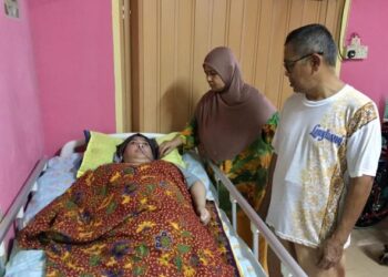 MUSTAFA Abdullah dan Romlah Salleh sentiasa berada di sisi  Ramilawati yang terlantar akibat lumpuh  di rumah mereka sejak tahun 2007 di Kampung Mengabang Telong, Setiu. - UTUSAN/TENGKU DANISH BAHRI TENGKU YUSOFF