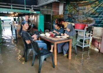 MOHD. MAIZATUL NAHAR JOHARI (kiri) dan dua rakannya menjamu selera di Restoran Bawah Kolong di Kampung Melayu 2, Kluang walaupun dinaiki air banjir.