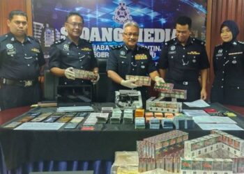 WAN Rukman Wan Hassan (tengah) menunjukkan sebahagian hasil rampasan daripada sindiket rokok seludup dan pinjaman wang  secara haram di Kuala Terengganu, semalam.