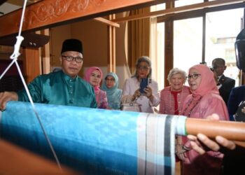MD. GHAFAWI Mat Said (kiri) menunjukkan sebahagian kain hiasan dinding yang sedang ditenun dan akan dipamerkan di dinding Suruhanjaya Malaysia di London sempena London Craft Week di London. Ia turut disaksikan oleh Tunku Azizah Aminah Maimunah Iskandariah (kanan). -IHSAN/ISTANA NEGArA