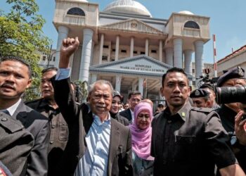 Muhyiddin Yassin diiringi isteri, Puan Sri Noorainee Abdul Rahman mengangkat tangan kepada penyokongnya ketika keluar dari mahkamah selepas membayar ikat jamin RM2 juta atas enam pertuduhan salah guna kuasa dan pengubahan wang haram di Kompleks Mahkamah Kuala Lumpur, semalam. – UTUSAN/MUHAMAD IQBAL ROSLI