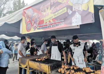 ABDUL Wafi Zainuddin (kanan) membakar ayam pusing madu Sarawak di bazar Ramadan Dataran Shahbandar di Kuala Terengganu, semalam.