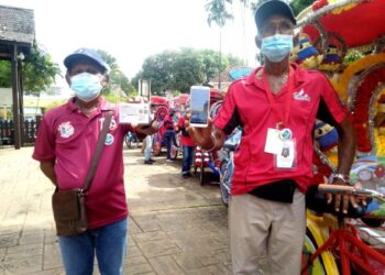 SULAIMAN Abd. Wahab (kiri) dan Hararana Jeet Singh menunjukkan kad dan sijil digital vaksinasi ketika ditemui pada program penyerahan kit makanan dan cegah Covid-19 di Banda Hilir, Melaka. - FOTO/MUHAMMAD SHAHIZAM TAZALI