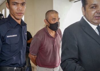 TERTUDUH, Chan Kam Kin diiringi anggota polis dan peguam ketika tiba di Mahkamah Majistret Petaling Jaya untuk didakwa atas pertuduhan mencampak seekor kucing dari tingkat 15 pangsapuri pada Isnin lalu. - UTUSAN/MUHAMAD IQBAL ROSLI