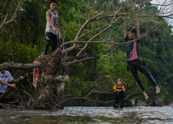 GELAGAT beberapa remaja yang memanjat dan bergayut di ranting kering ketika bermain di kawasan Air Terjun Sekayu, Hulu Terengganu, kelmarin. – UTUSAN/PUQTRA HAIRRY