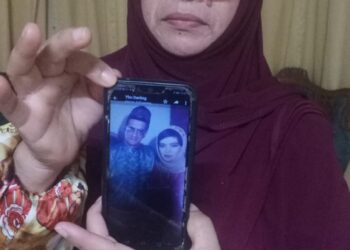 NORAIDAH Othman menunjukkan gambar kakaknya, Faridah bersama suaminya pada 1993 ketika ditemui di rumahnya di Taman Desa Permai, Seri Manjung, Lumut, Perak, hari ini. - UTUSAN/SHAMSUL KAMAL AMARUDIN