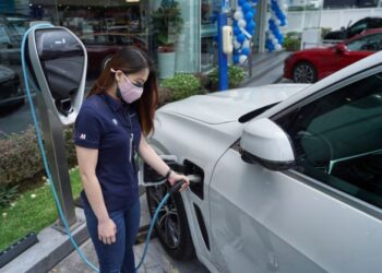 Penasihat Jualan, Song Bun Mun membantu mengecas kereta elektrik milik pelanggannya di Pusat Jualan Auto Bavaria, Jalan Tun Razak di sini, baru-baru ini. -UTUSAN/MUHAMAD IQBAL ROSLI