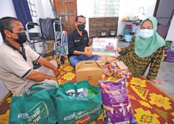 AZLAN JAAFAR menyampaikan bantuan kepada Sapiah Keweh, sambil diperhatikan oleh anaknya di Ulu Bendul, Kuala Pilah, baru-baru ini.
