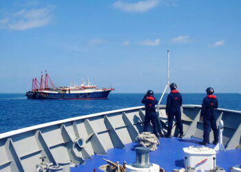 KAPAL pengawal pantai Filipina mengawasi sebuah kapal China yang berlabuh di Laut China Selatan. - AFP