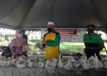 RAZMAN Zakaria (tengah) menyampaikan daging korban kepada seorang petugas barisan hadapan untuk diagihkan kepada penghuni Apartmen Tropicana Bukit Merah yang dikenakan PKPD di Bagan Serai hari ini. - UTUSAN/WAT KAMAL ABAS