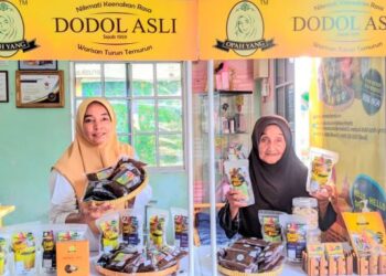 SAERAH (kanan) dan anaknya, Normi Mohd. Ramli menunjukkan produk Dodol Opah Yang yang semakin mendapat sambutan ketika ditemui di Teluk Sareh, Kampung Gajah dekat Pasir Salak baru-baru ini.  -UTUSAN/MOHAMAD HAFIZI MOHD. SAID