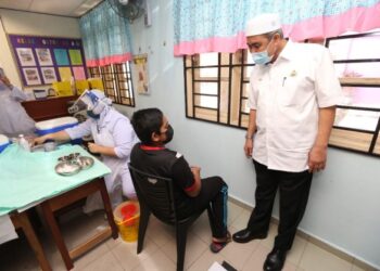 DR. IZANI Husin bertanya khabar seorang murid selepas dia menerima suntikan vaksin Covid-19 di SK Demit 2, Panji, Kota Bharu, Kelantan, hari ini. - FOTO/ROHANA MOHD. NAWI