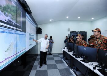 AMINUDDIN Harun (dua dari kanan) mendengar penerangan mengenai pengoperasian NeSCOM selepas merasmikan bangunan pusat operasi tersebut yang terletak di Jalan Pekeliling, Seremban hari ini.-UTUSAN/MOHD. SHAHJEHAN MAAMIN.