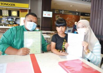 MOHD. Fairuz dan Siti Aisah bersama anak angkat mereka Nurul Ain Safikah menunjukkan sijil kelahiran dan dokumen berkaitan bagi mencari ayah kandung Nurul Ain Safikah iaitu Hazmain Abdul Jalil ketika ditemui Utusan Malaysia di Seremban, semalam.-UTUSAN/ZAKKINA WATI AHMAD TARMIZI