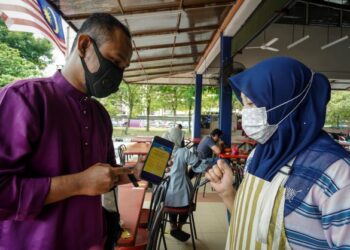 PENGUSAHA kedai makan, Umi Kalsum Zakaria memeriksa sijil digital vaksinasi seorang pelanggan, Muhamad Hanif Ramly menerusi aplikasi MySejahtera di Medan Selera Bandar Sri Permaisuri, Kuala Lumpur, semalam.– UTUSAN/FARIZ RUSADIO