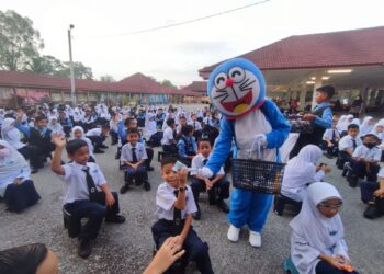 NURULAZMA Shafiqah Khairul Azhar yang memakai kostum Doraemon mengagihkan bungkusan coklat kepada murid-murid SK Serting Ilir di Jempol, semalam. – UTUSAN/NOR AINNA HAMZAH