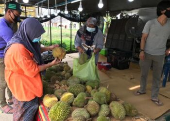 TENGKU Nor Amira nelayan pelanggan yang datang membeli buah durian di gerai milik keluarganya di Pengkalan Kubor, Tumpat. - FOTO/ROSLIZA MOHAMED