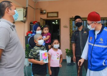 ZULKIFLI Mohamad Al-Bakri menyampaikan sumbangan tablet komputer kepada Muhammad Adam Naufal Mohd. Hiran,9, pada Program Sumbangan Dana Perlu dan Dana Pelajar Yayasan Wakaf Malaysia (YKM) di Taman Mantau Indah, Seremban hari ini.-UTUSAN/MUHAMMAD IZZAT TERMIZIE