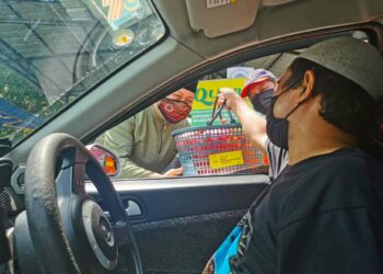 MOHD. RIDHWAN Mohd. Ali mengagihkan pek daging korban kepada orang ramai di hadapan Masjid Al-Alami MITC, Melaka. - UTUSAN/DIYANATUL ATIQAH ZAKARYA